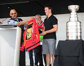 Grand Chief Ron Evans presents a red ribbon shirt to Jonathan Toews