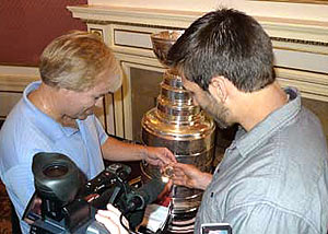 Hockey Hall of Fame Curator and Cup Keeper Phil Pritchard presents Patrice Bergeron with a commerative Tissot gold watch after becoming the 25th member of the Triple Gold Club.
