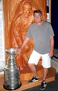Cam Neely and the Stanley Cup posing for a photo in front of a Spirit of Wood Sport Hero Carving of Neely on display at the Cam Neely Arena in Maple Ridge, BC.