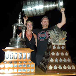 Tim Thomas and his wife Melissa sharing a moment with the Stanley Cup, Vezina and Conn Smythe trophies.