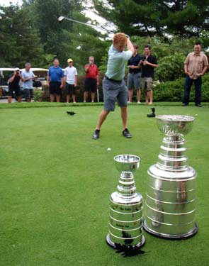 The Stanley Cup and Molson Cup look on as Brian Campbell tees off at the Oaks Golf and Country Club.