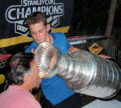 Tyler Seguin helping a family friend enjoy a drink from the bowl of the Stanley Cup.