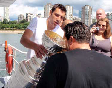 Milan Lucic helping one of his guests aboard the 'Harbour Princess' enjoy a drink from the bowl of the Stanley Cup.