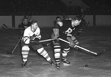 Fern Flaman of the Toronto Maple Leafs battling with Milt Schmidt of the Boston Bruins.