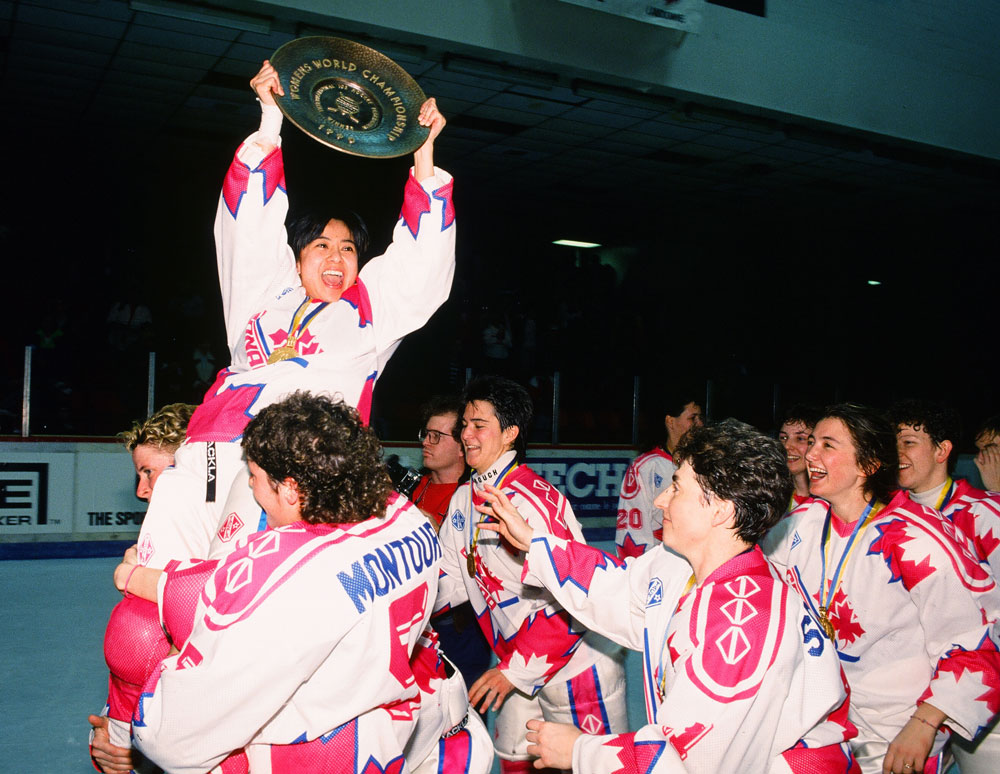 Susie Yuen of Canada is raised into the air by her teammates while holding the 1990 IIHF Ice Hockey Women’s World Championship plate above her head. Credit: Claus Anderson