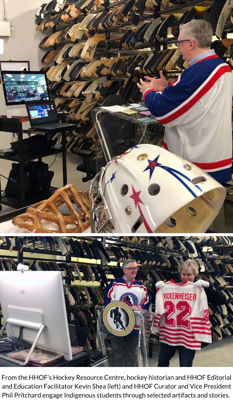 Against a background of the stick wall at the Resource Centre, Kevin Shea and Phil Pritcard stand behind a Hockey Hall of Fame podium presenting a Hayley Wickenheiser jersey. They are facing a computer with a web cam.